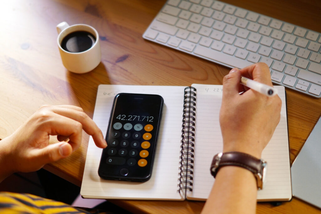 A new Amazon seller is calculating figures and taking notes, emphasizing the financial planning needed to start selling on Amazon.