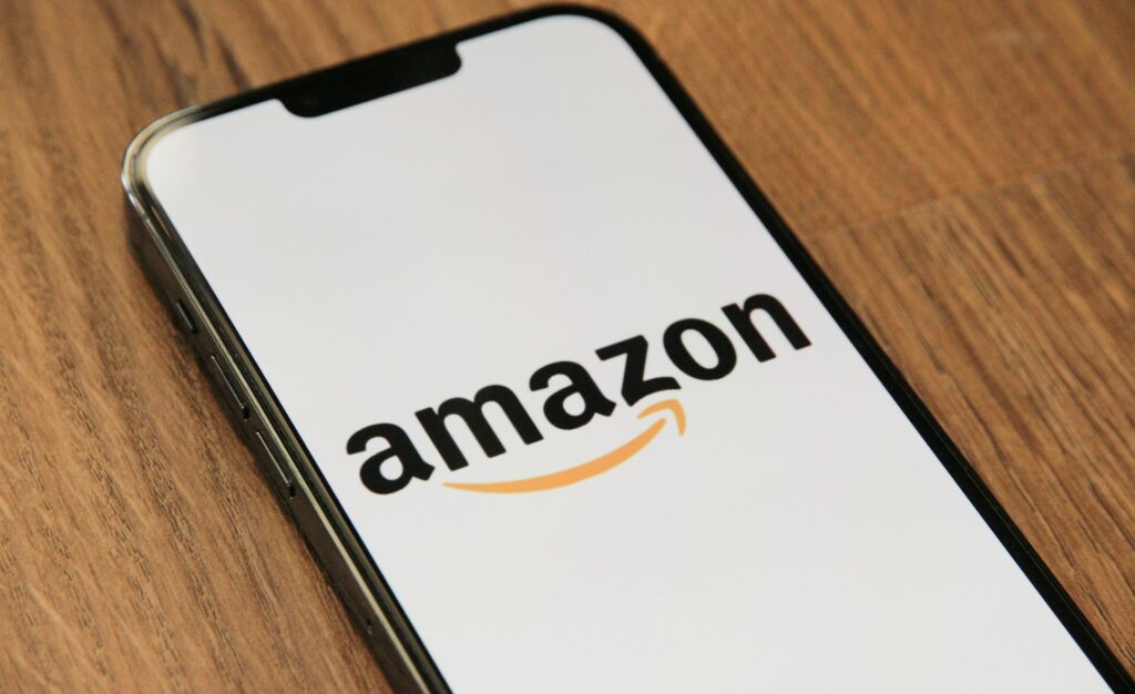 Amazon seller central - a close-up of a smartphone displaying the Amazon logo on a white screen, resting on a wooden surface.