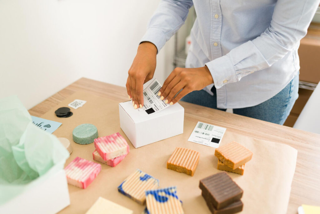 Amazon FBA white label - Hands applying a barcode label to a product box with white-label soap