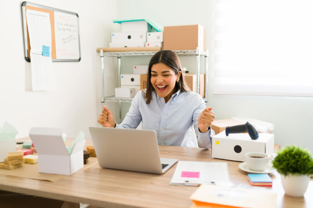 Get ungated on Amazon - An excited seller celebrates being ungated in front of laptop