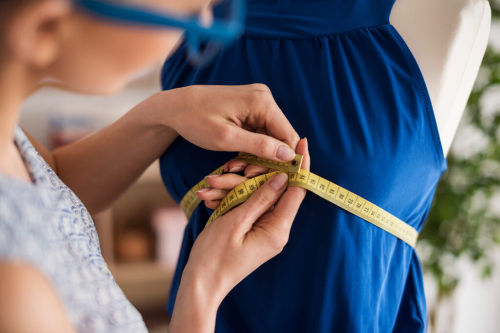 Asian sizes to US sizes - A person using a tape measure to get clothing dimensions