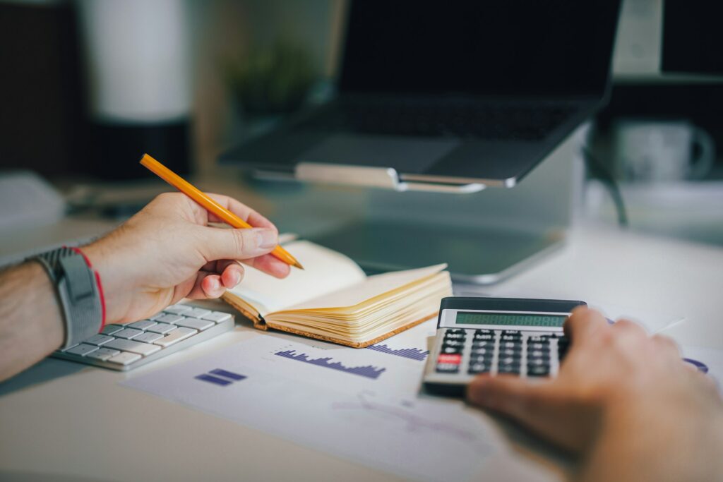 Amazon tax filing - A person using a calculator and notebook to do financial work