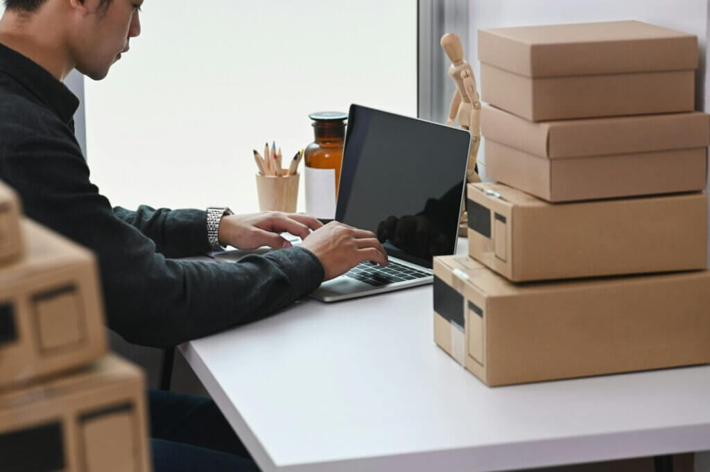 Best Amazon PPC software - A seller working on a laptop surrounded by boxes
