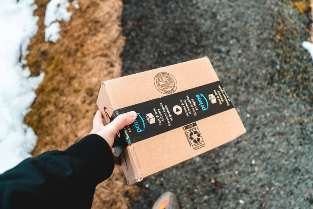 Amazon seller fulfilled prime - A hand holding a small Amazon Prime delivery box outdoors