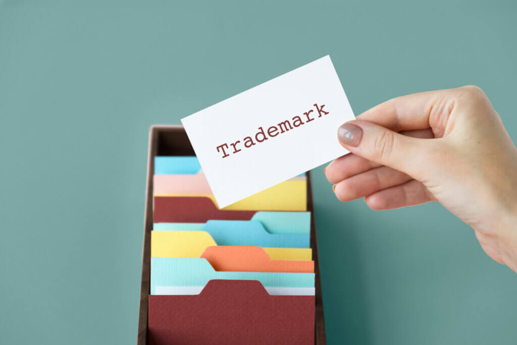 Trademarks for Amazon sellers - A hand holding a white card with the word "Trademark" above a folder organizer with colorful tabs