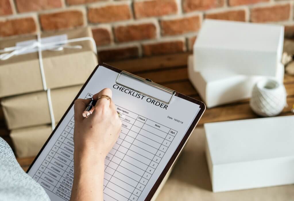 inventory-turnover-ratio-amazon-fba - A person filling out an order checklist surrounded by shipping boxes.