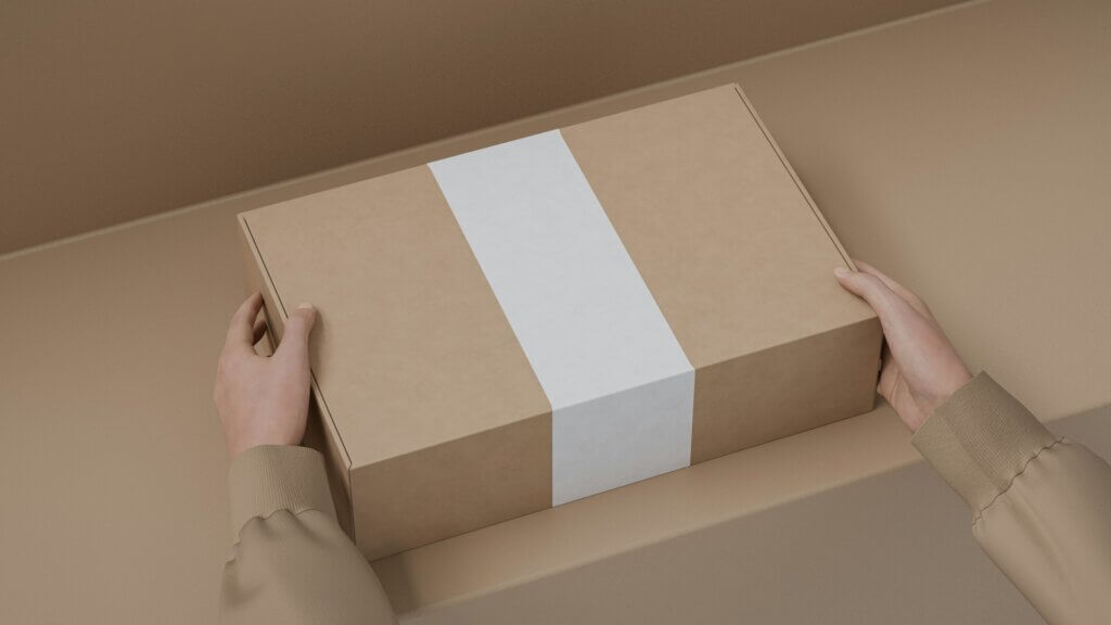 Hands holding a cardboard shipping box with a blank label, representing brand product fulfillment