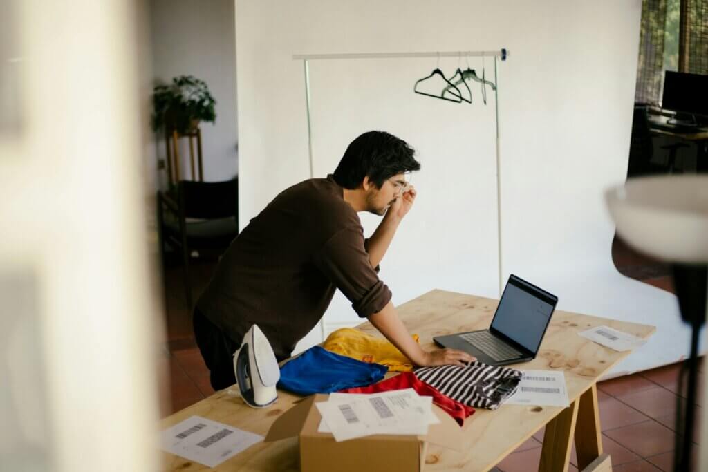 ai workflows - seller reviewing AI Operator workflows on a laptop while packing a shipment