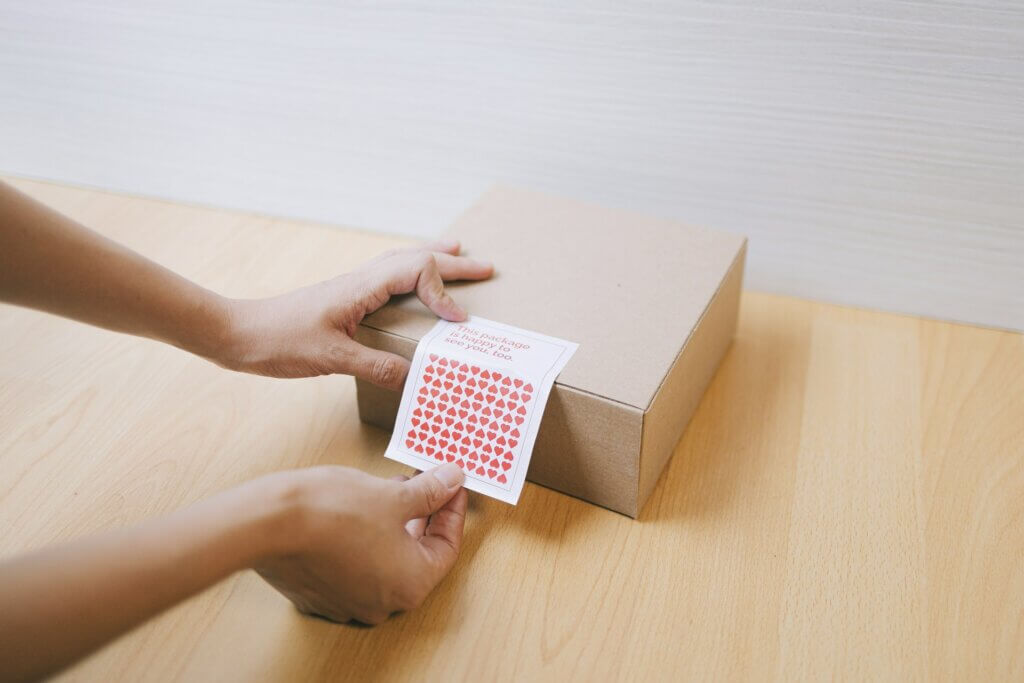 decisions amazon sellers make daily - Hands applying a heart sticker sheet to a cardboard box