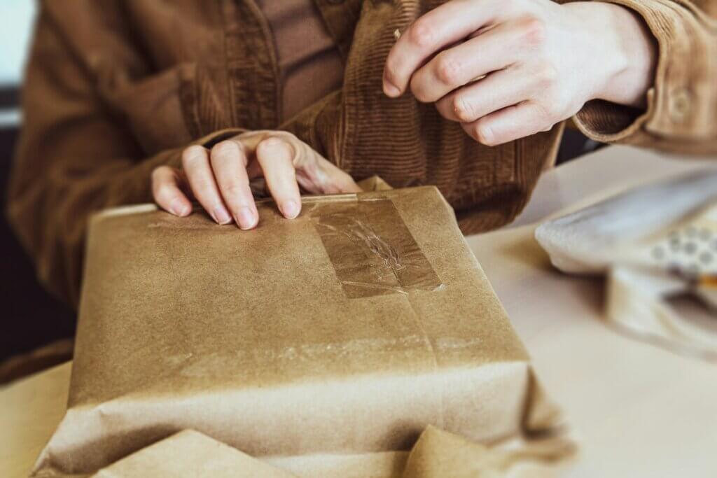 An Amazon FBA seller packing an item using a brown paper to sell online